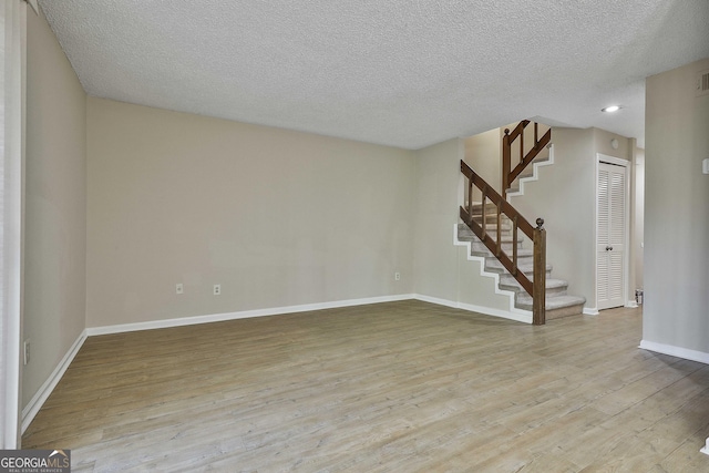 empty room with a textured ceiling and light hardwood / wood-style flooring