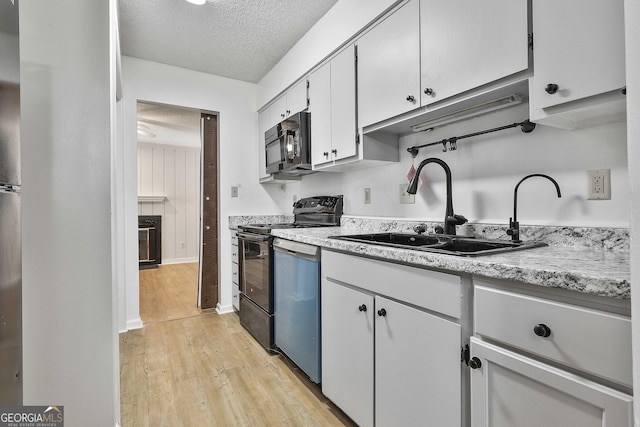 kitchen with light hardwood / wood-style floors, black appliances, sink, a textured ceiling, and white cabinets