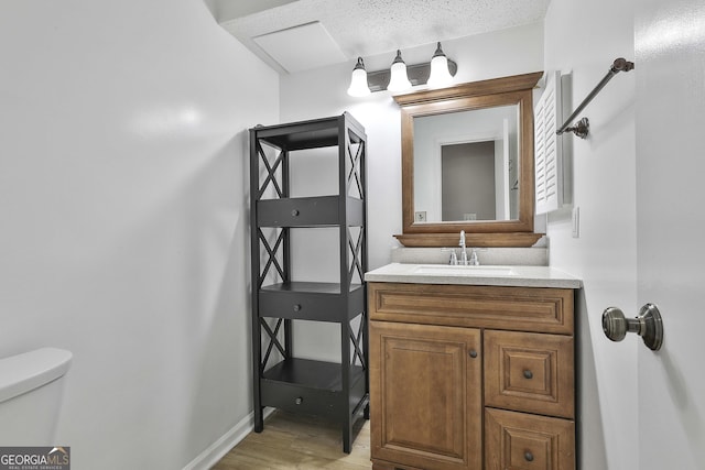 bathroom with a textured ceiling, toilet, vanity, and hardwood / wood-style floors