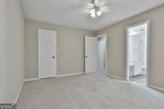 unfurnished bedroom with ceiling fan, light colored carpet, and ensuite bath