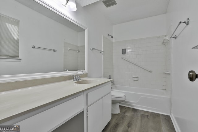 full bathroom featuring toilet, tiled shower / bath combo, wood-type flooring, and vanity