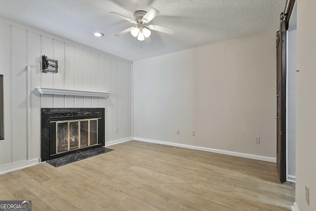 unfurnished living room with a textured ceiling, ceiling fan, and light wood-type flooring