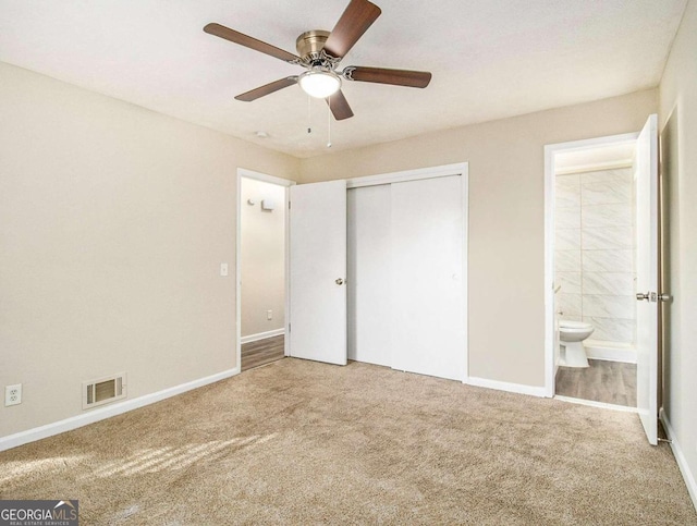 unfurnished bedroom with ceiling fan, a closet, carpet, and ensuite bathroom