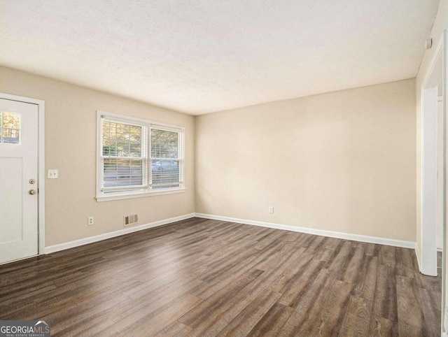3811 Paul St, Douglasville, GA 30135 - unfurnished living room featuring dark wood-type flooring, baseboards, and a textured ceiling