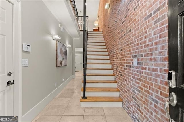 stairs featuring tile patterned flooring and brick wall