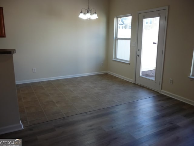 unfurnished dining area featuring a notable chandelier and dark wood-type flooring