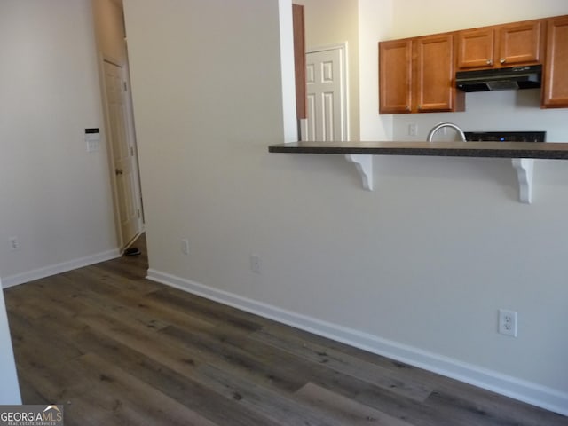 kitchen with a kitchen breakfast bar, dark hardwood / wood-style floors, and kitchen peninsula