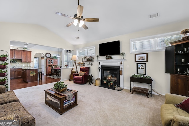 carpeted living room with ceiling fan and lofted ceiling