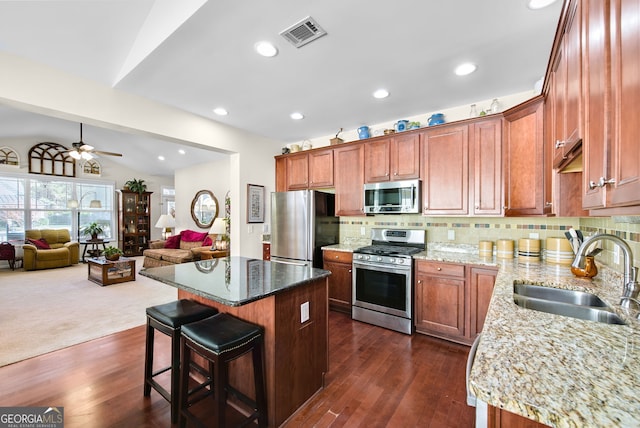 kitchen with a kitchen island, sink, light stone countertops, and stainless steel appliances