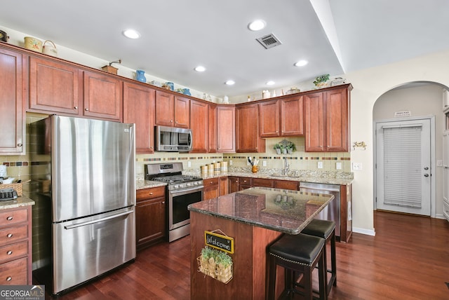 kitchen featuring a center island, dark stone counters, dark hardwood / wood-style floors, and appliances with stainless steel finishes