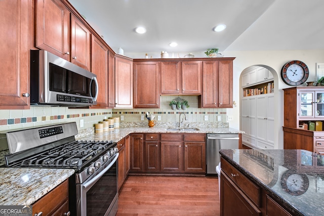 kitchen featuring light stone counters, sink, stainless steel appliances, and light hardwood / wood-style flooring