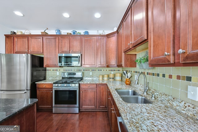 kitchen with light stone countertops, sink, dark hardwood / wood-style floors, backsplash, and appliances with stainless steel finishes