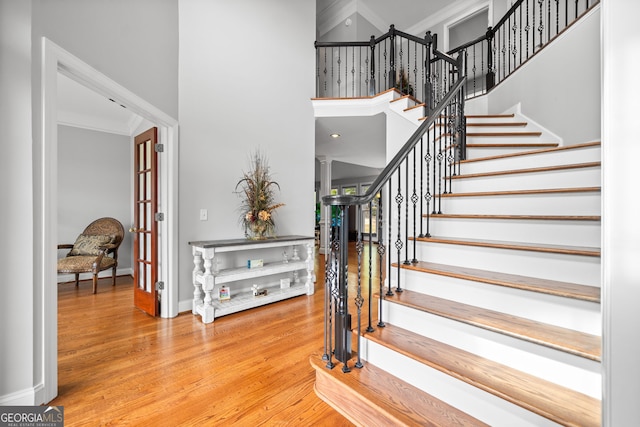 staircase with hardwood / wood-style floors and ornamental molding