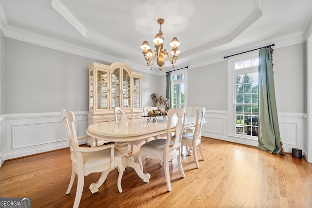 dining room with light wood-type flooring, crown molding, a tray ceiling, and a chandelier