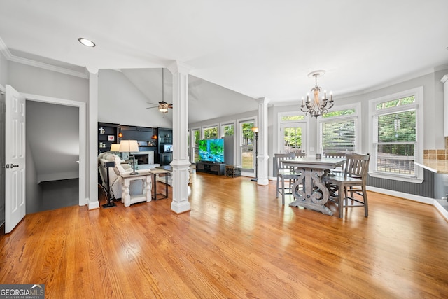 dining room with light hardwood / wood-style flooring, decorative columns, crown molding, vaulted ceiling, and ceiling fan with notable chandelier