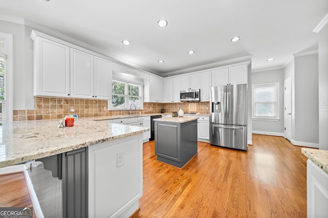 kitchen featuring white cabinets, a kitchen island, light stone countertops, and appliances with stainless steel finishes