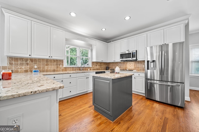 kitchen featuring a kitchen island, light stone counters, a healthy amount of sunlight, and appliances with stainless steel finishes