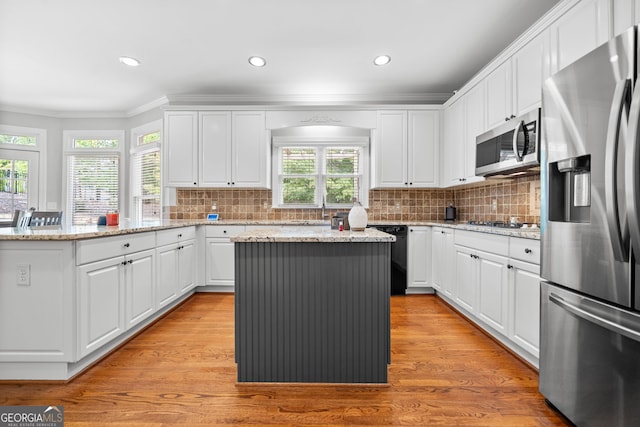 kitchen with a center island, stainless steel appliances, plenty of natural light, and light hardwood / wood-style floors