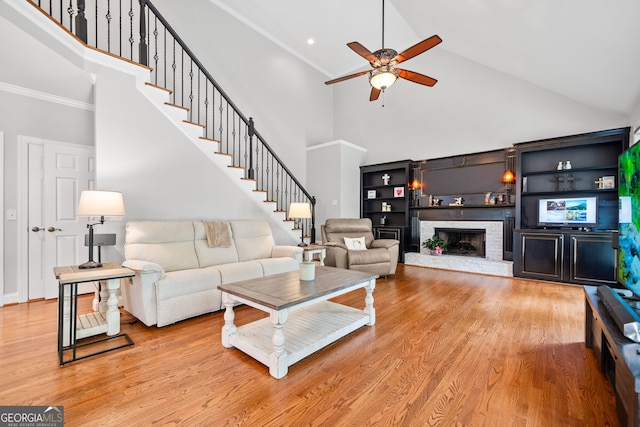 living room featuring a brick fireplace, light wood-type flooring, high vaulted ceiling, and ceiling fan