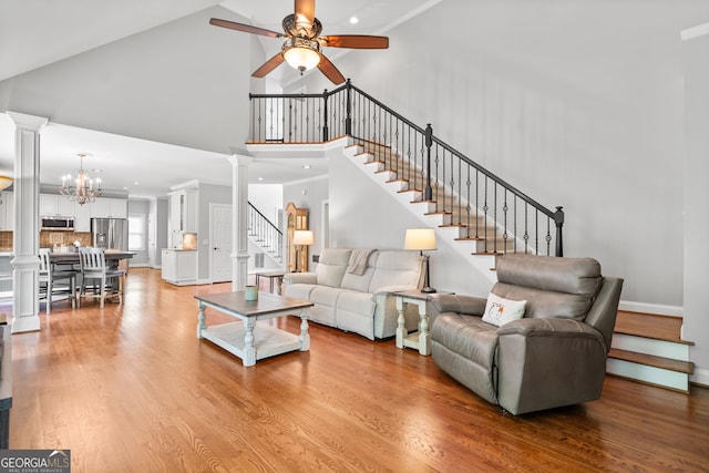 living room featuring ceiling fan with notable chandelier, light wood-type flooring, and high vaulted ceiling