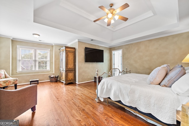 bedroom featuring a raised ceiling, ceiling fan, crown molding, and light hardwood / wood-style floors