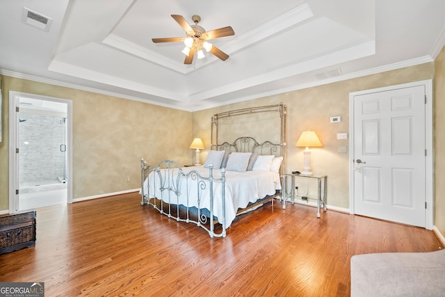 bedroom with ensuite bathroom, a raised ceiling, ceiling fan, crown molding, and wood-type flooring