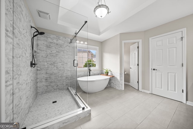 bathroom with a tray ceiling, tile patterned floors, and independent shower and bath