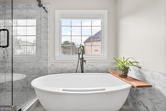 bathroom with a bathing tub and tile walls