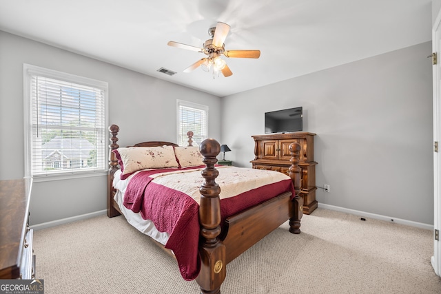 bedroom with ceiling fan, light carpet, and multiple windows