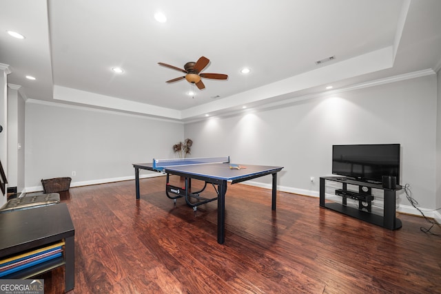 game room with ceiling fan, dark hardwood / wood-style flooring, crown molding, and a tray ceiling