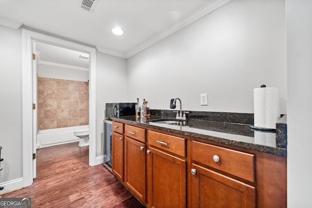 kitchen with dark hardwood / wood-style floors, ornamental molding, sink, and dark stone counters