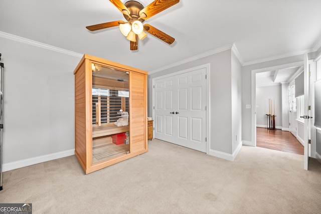 carpeted bedroom featuring crown molding, a closet, and ceiling fan