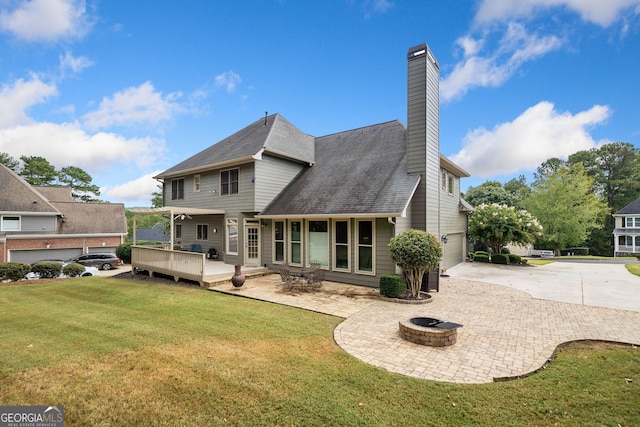 rear view of property with a yard, a fire pit, a deck, a garage, and a patio area