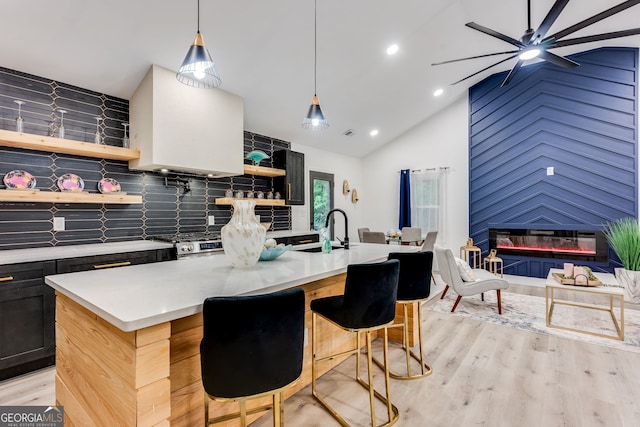 kitchen featuring a kitchen bar, light wood-type flooring, a large fireplace, and an island with sink