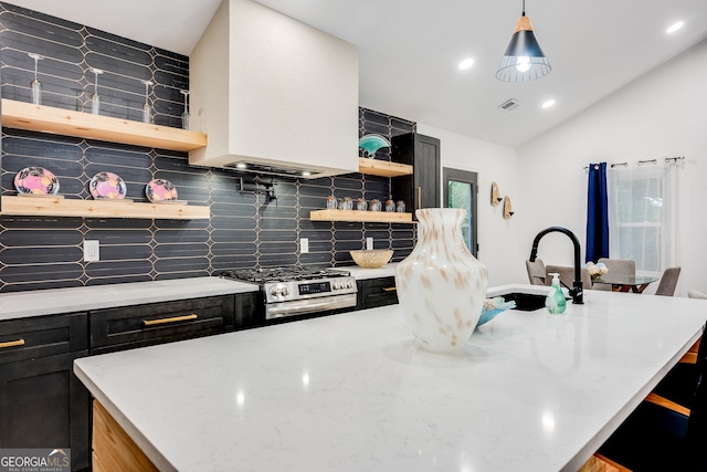 kitchen featuring decorative backsplash, light stone counters, a breakfast bar, gas stove, and decorative light fixtures