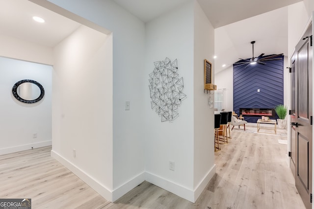 hall featuring light wood-type flooring and vaulted ceiling