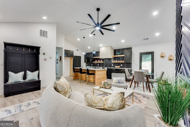 living room with light hardwood / wood-style floors, ceiling fan, and lofted ceiling