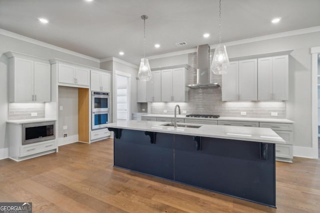 kitchen featuring white cabinetry, sink, wall chimney range hood, and light wood-type flooring