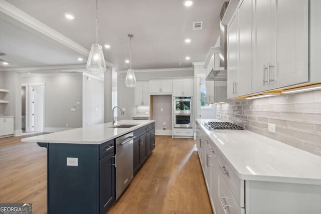 kitchen featuring a center island with sink, sink, hanging light fixtures, appliances with stainless steel finishes, and white cabinetry