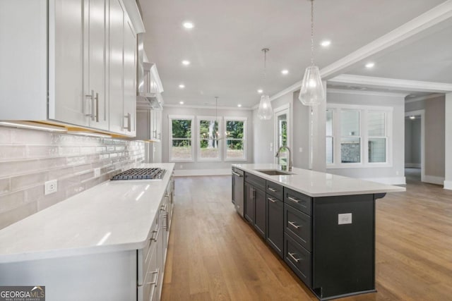 kitchen featuring sink, white cabinetry, an island with sink, and hanging light fixtures