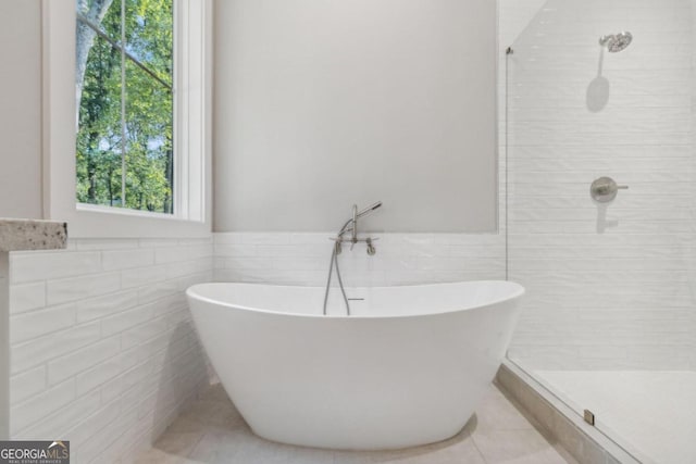 bathroom with tile patterned flooring, tile walls, and independent shower and bath