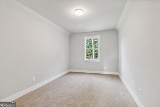 carpeted spare room featuring vaulted ceiling