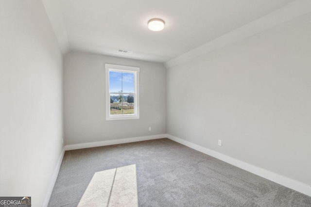 carpeted empty room featuring lofted ceiling