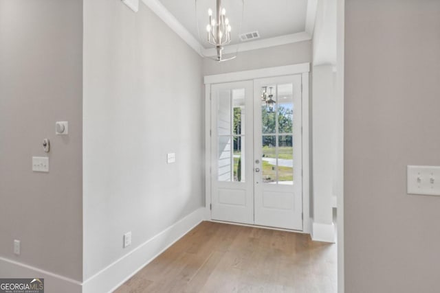 foyer entrance featuring a notable chandelier, light wood-type flooring, and crown molding