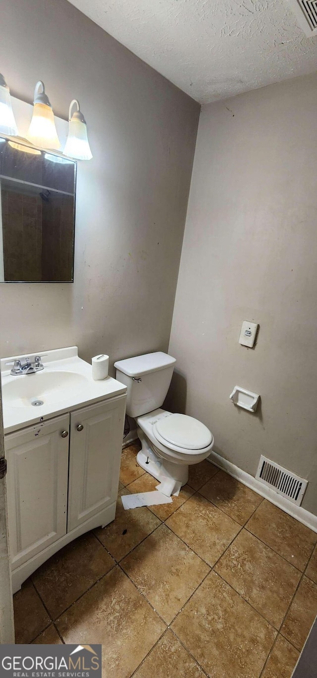 bathroom with a textured ceiling, vanity, and toilet