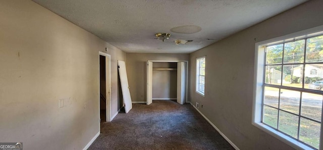 unfurnished bedroom with dark colored carpet and a textured ceiling