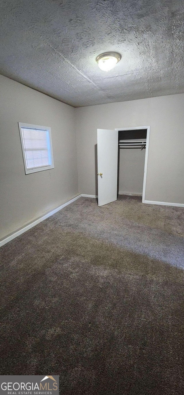 carpeted empty room featuring a textured ceiling