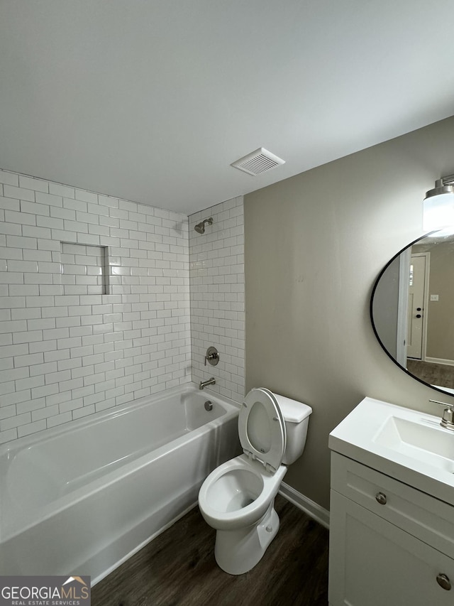 full bathroom with tiled shower / bath combo, vanity, hardwood / wood-style floors, and toilet