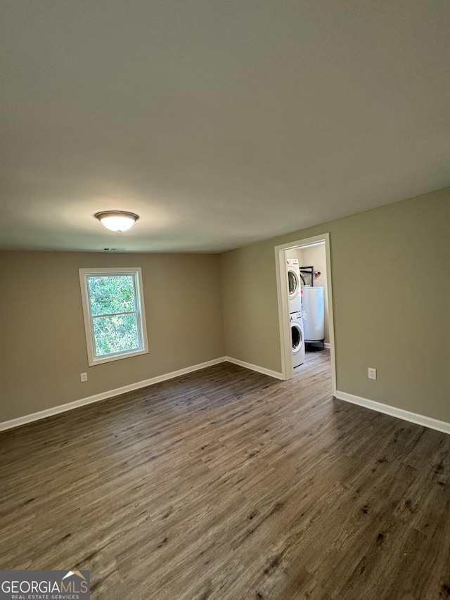 unfurnished room featuring dark wood-type flooring and stacked washer / dryer