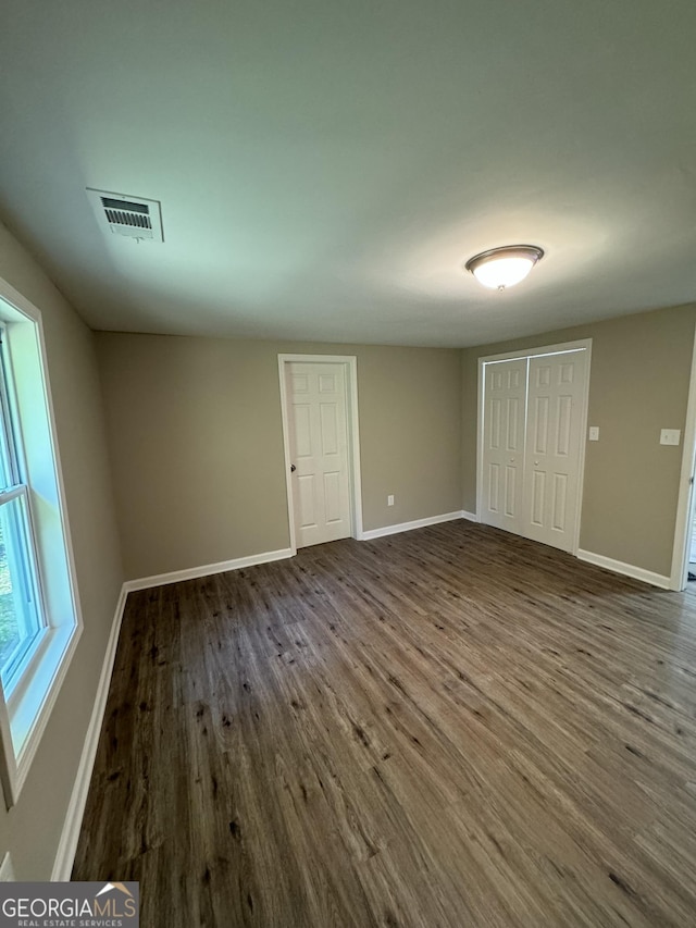 unfurnished bedroom with dark hardwood / wood-style flooring and a closet